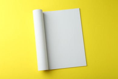 Photo of Open magazine with blank page on yellow background, top view. Mockup for design