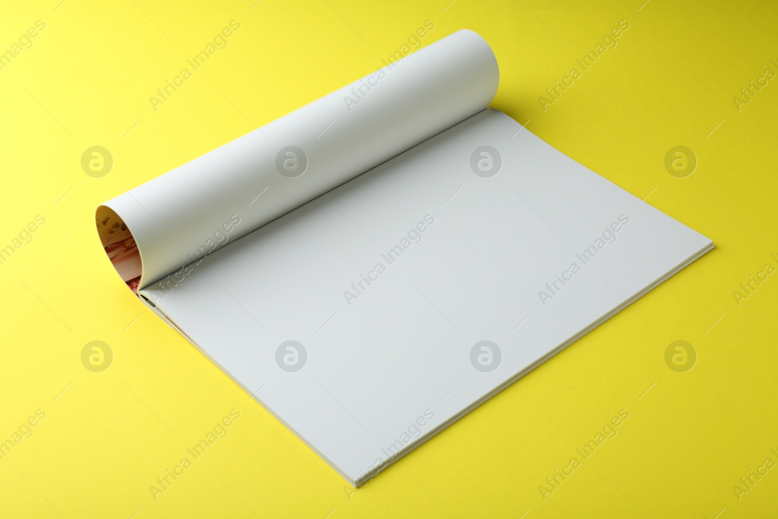 Photo of Open magazine with blank page on yellow background. Mockup for design