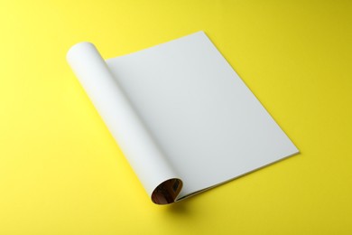 Open magazine with blank page on yellow background. Mockup for design