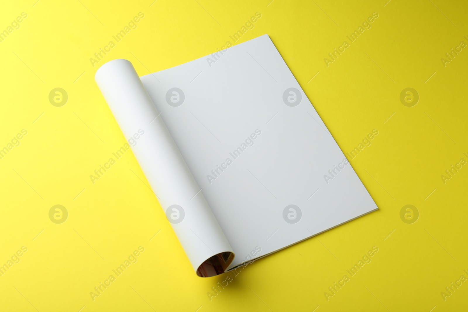 Photo of Open magazine with blank page on yellow background. Mockup for design