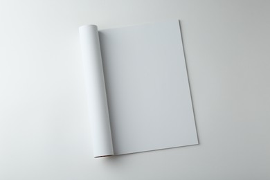 Open magazine with blank page on white background, top view. Mockup for design