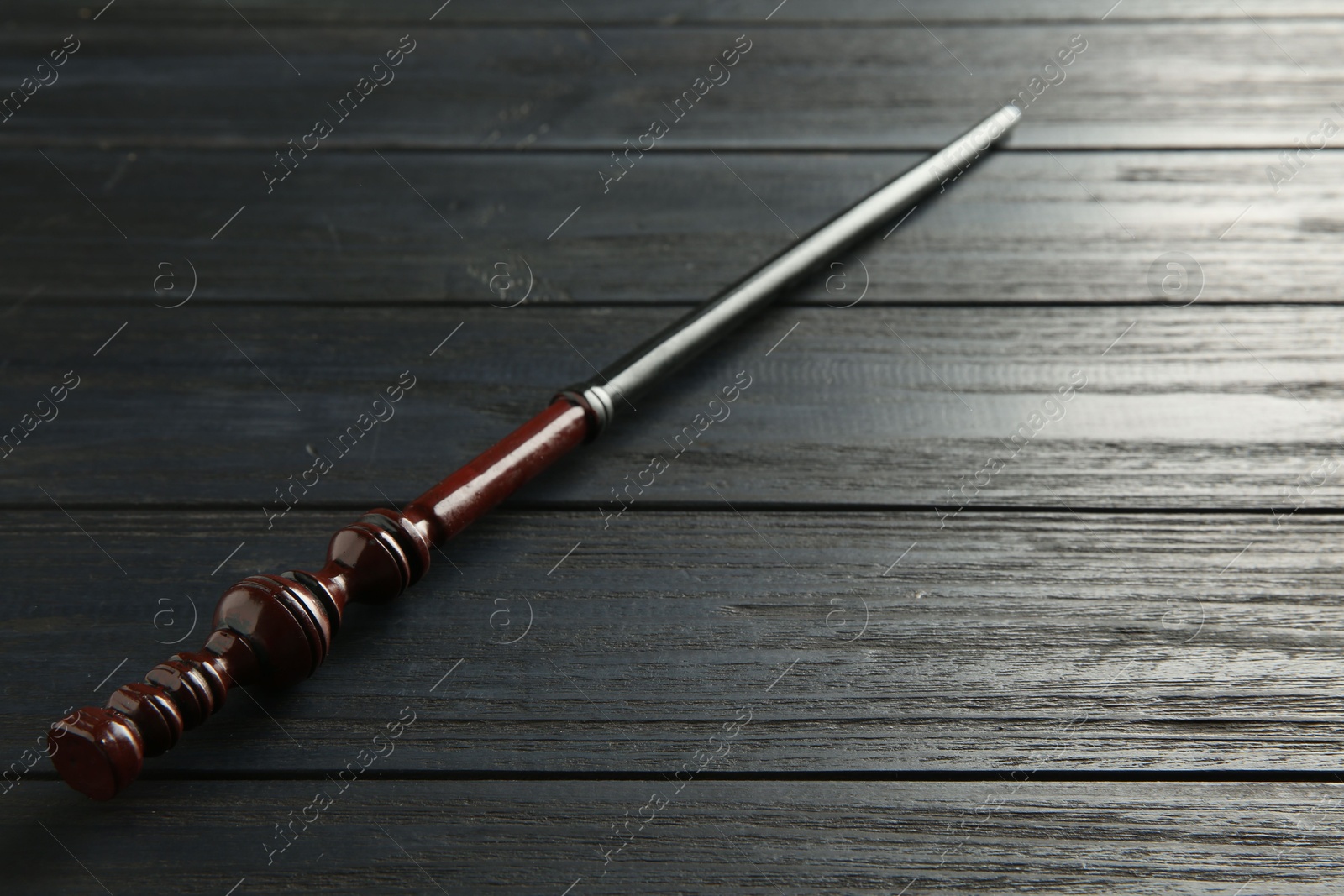 Photo of One old magic wand on wooden table, closeup