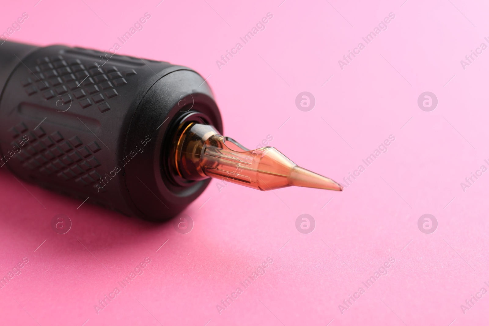 Photo of Professional permanent makeup machine on pink background, closeup