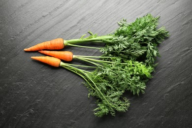 Photo of Tasty ripe juicy carrots on dark gray textured table, top view