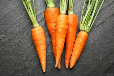 Tasty ripe juicy carrots on dark gray textured table, top view