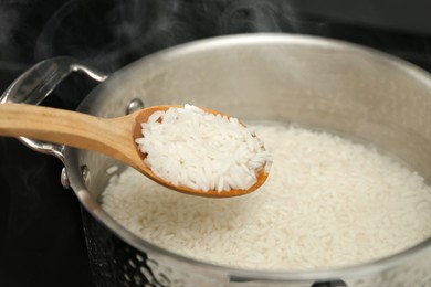 Photo of Taking boiled rice from pot with spoon, closeup