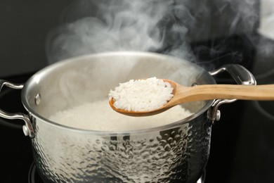 Photo of Taking boiled rice from pot with spoon, closeup