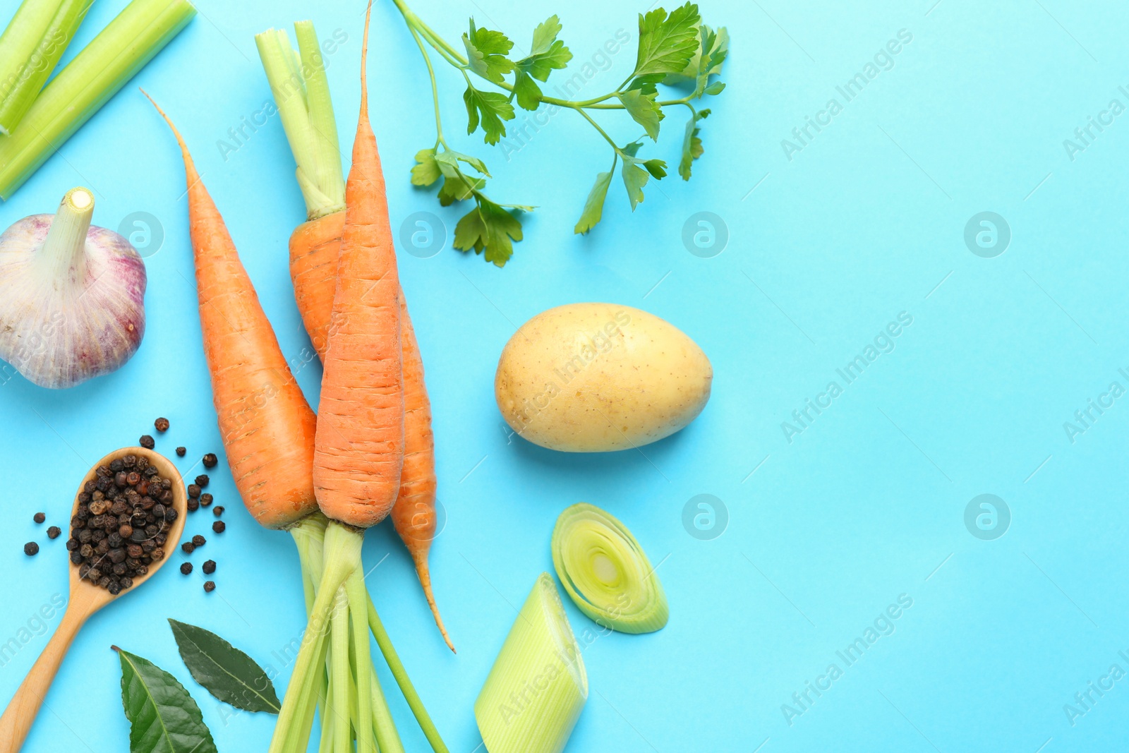 Photo of Fresh ripe carrots, vegetables, spices and spoon on light blue background, flat lay. Space for text