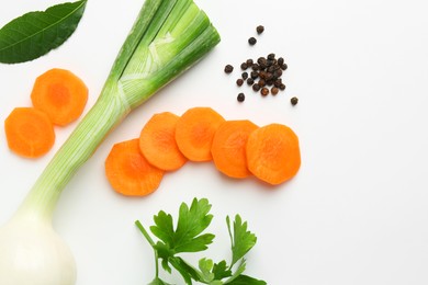 Pieces of fresh ripe carrot, onion and spices on white background, flat lay. Space for text