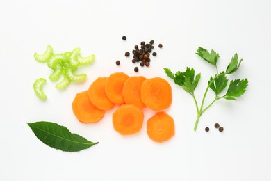 Photo of Pieces of fresh ripe carrot, celery and spices on white background, flat lay