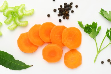 Photo of Pieces of fresh ripe carrot, celery and spices on white background, flat lay