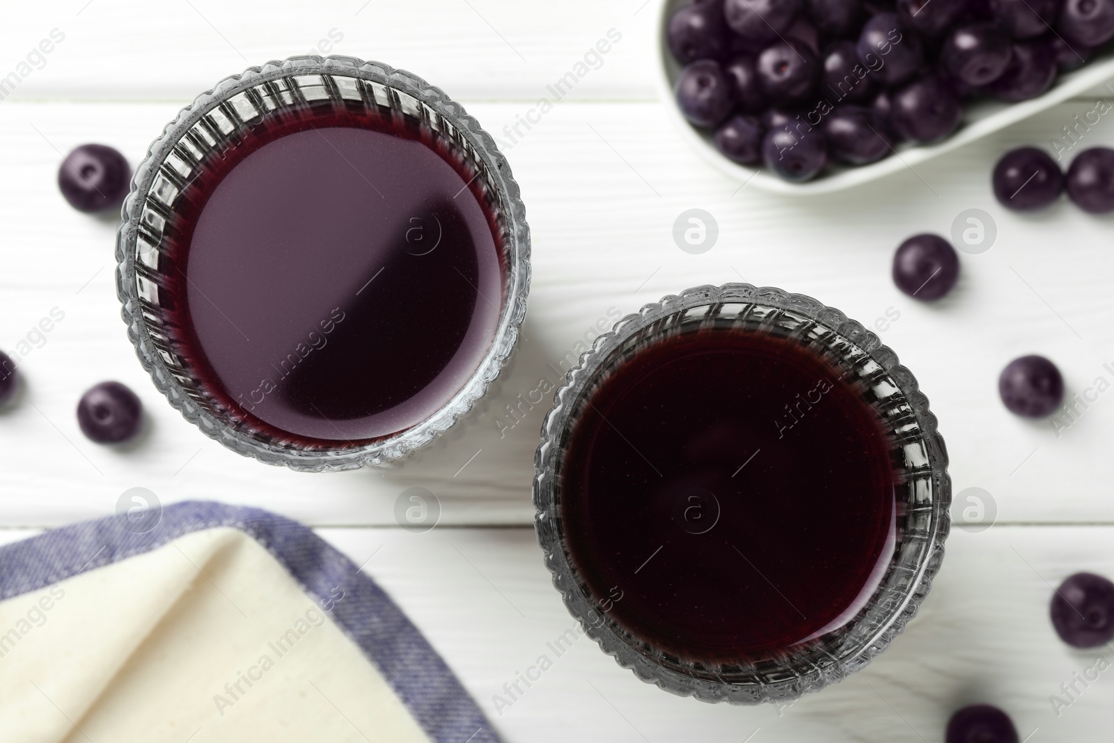 Photo of Delicious acai juice in glasses and berries on white wooden table, flat lay