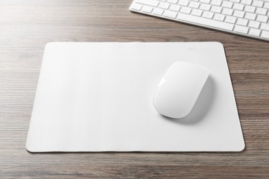 Photo of Computer mouse with mousepad and keyboard on wooden desk