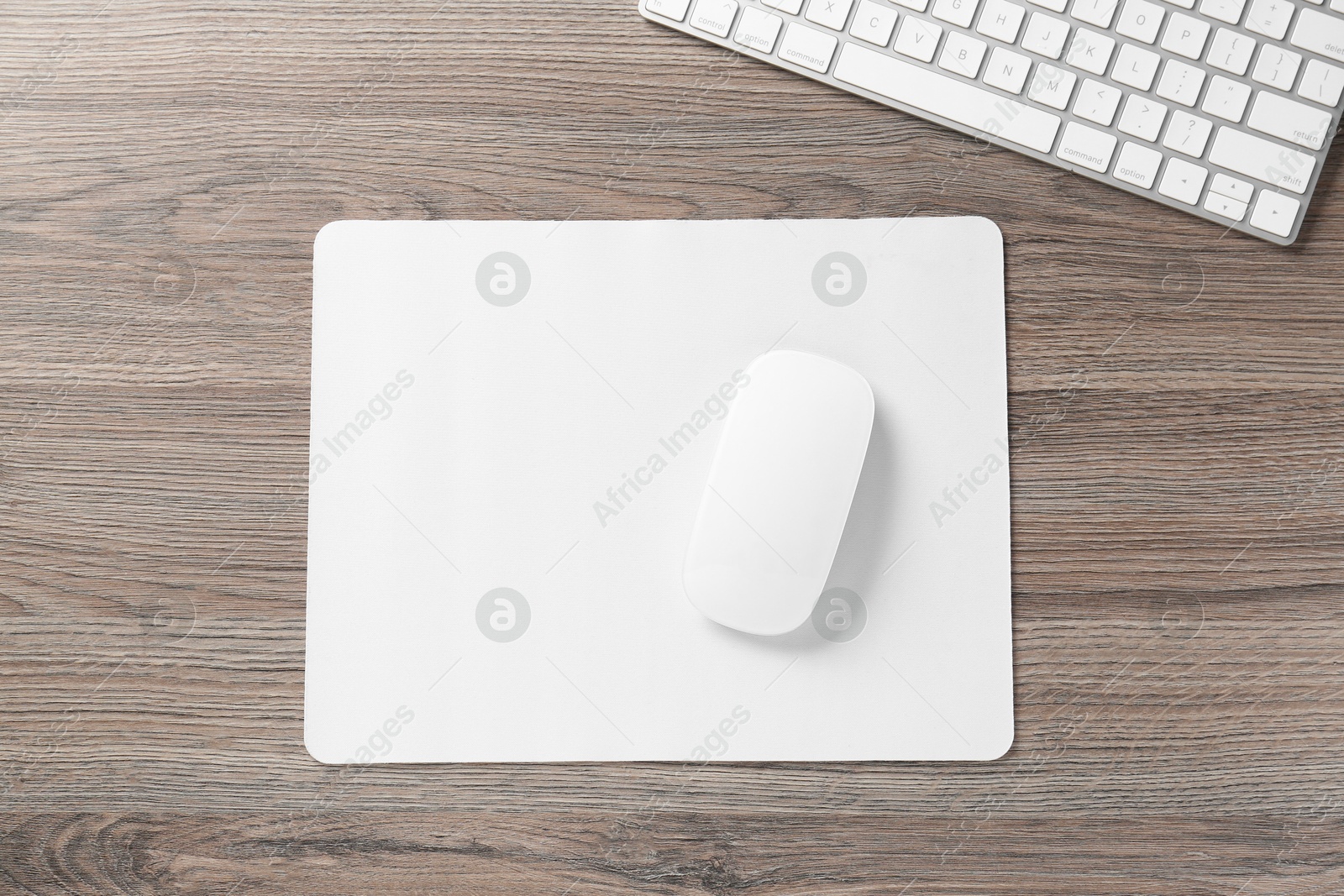 Photo of Computer mouse with mousepad and keyboard on wooden desk, top view