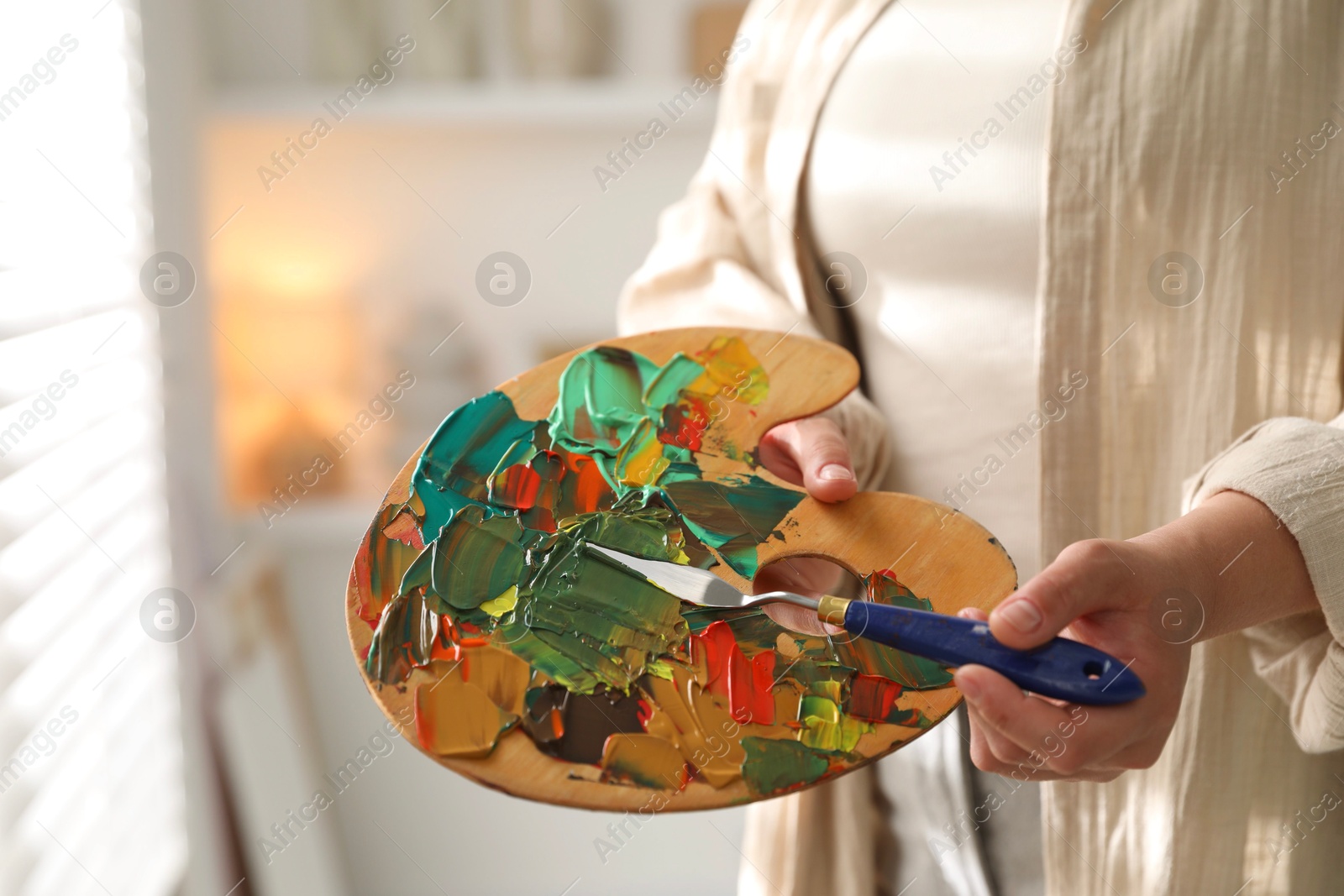 Photo of Woman with knife using palette indoors, closeup