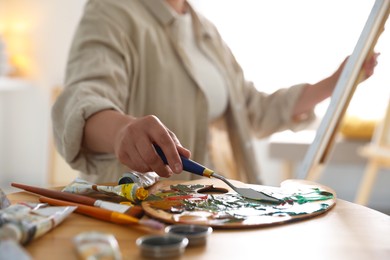 Photo of Woman with knife using palette at table indoors, closeup