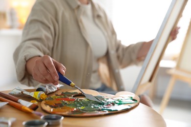 Photo of Woman with knife using palette at table indoors, closeup