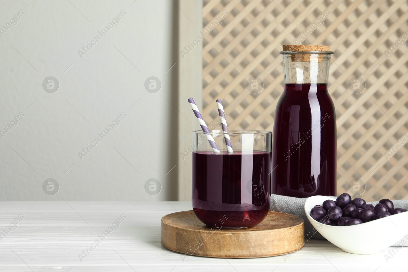 Photo of Delicious acai juice and berries on white wooden table. Space for text