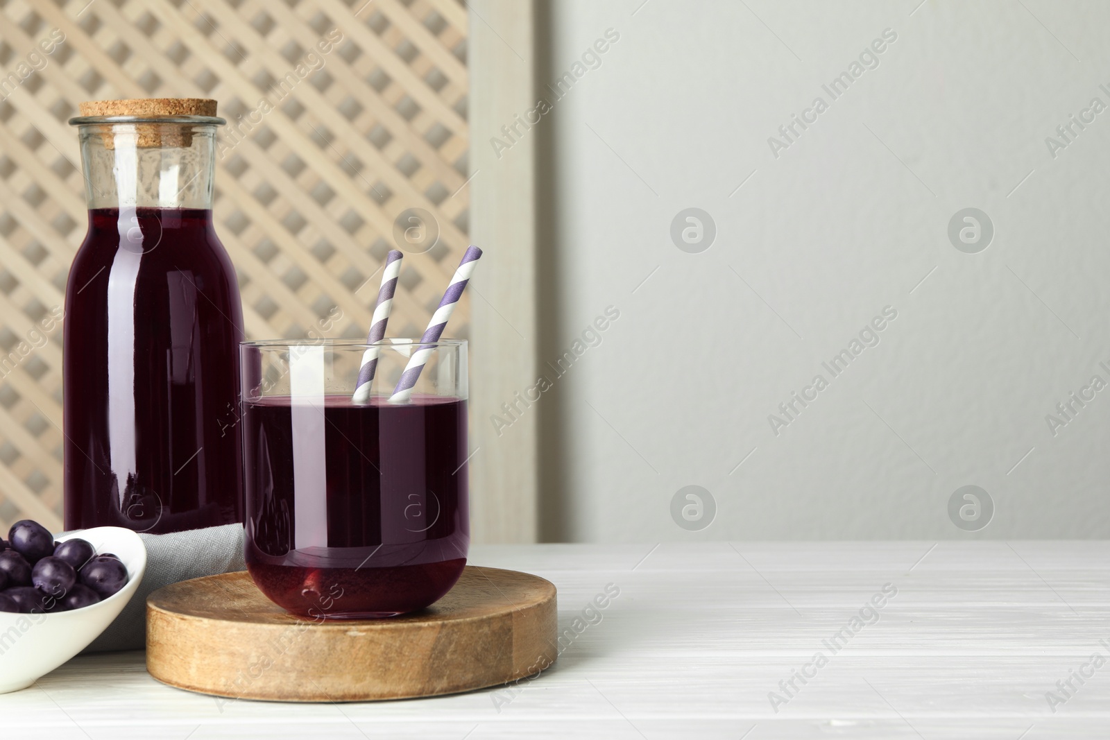 Photo of Delicious acai juice and berries on white wooden table. Space for text