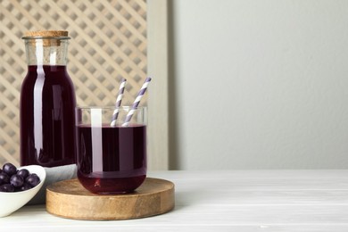 Photo of Delicious acai juice and berries on white wooden table. Space for text