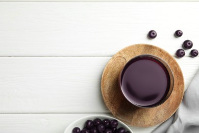 Photo of Delicious acai juice in glass and berries on white wooden table, flat lay. Space for text