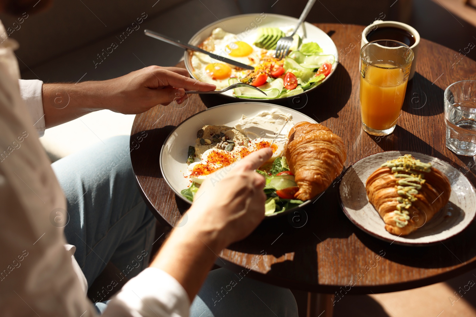 Photo of Man having tasty breakfast at wooden table in cafe, closeup