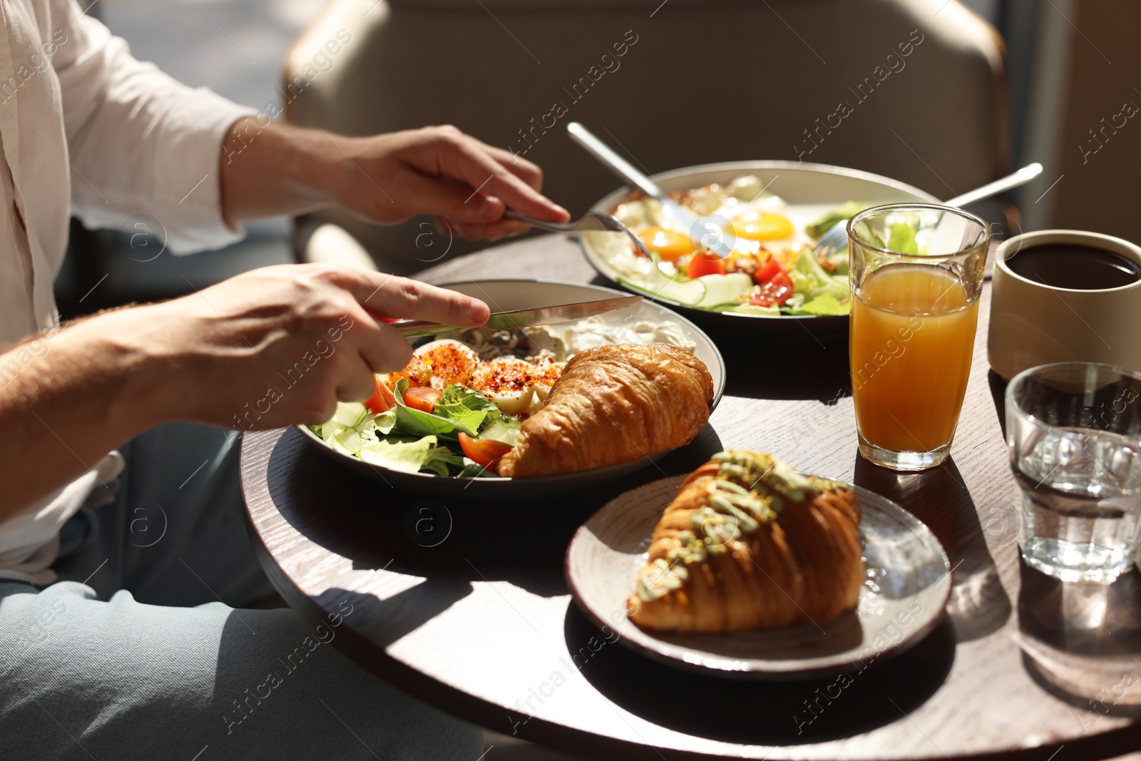 Photo of Man having tasty breakfast at wooden table in cafe, closeup