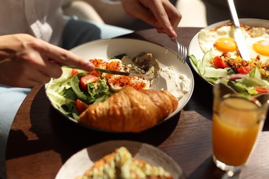 Photo of Man having tasty breakfast at wooden table in cafe, closeup