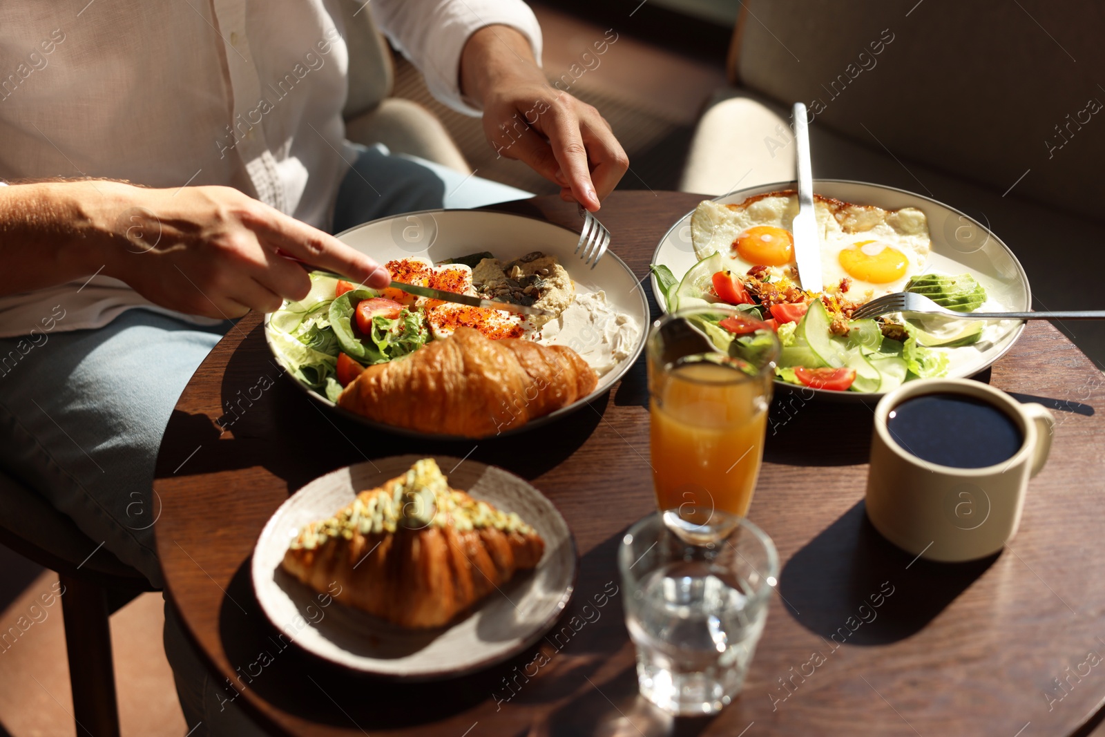 Photo of Man having tasty breakfast at wooden table in cafe, closeup