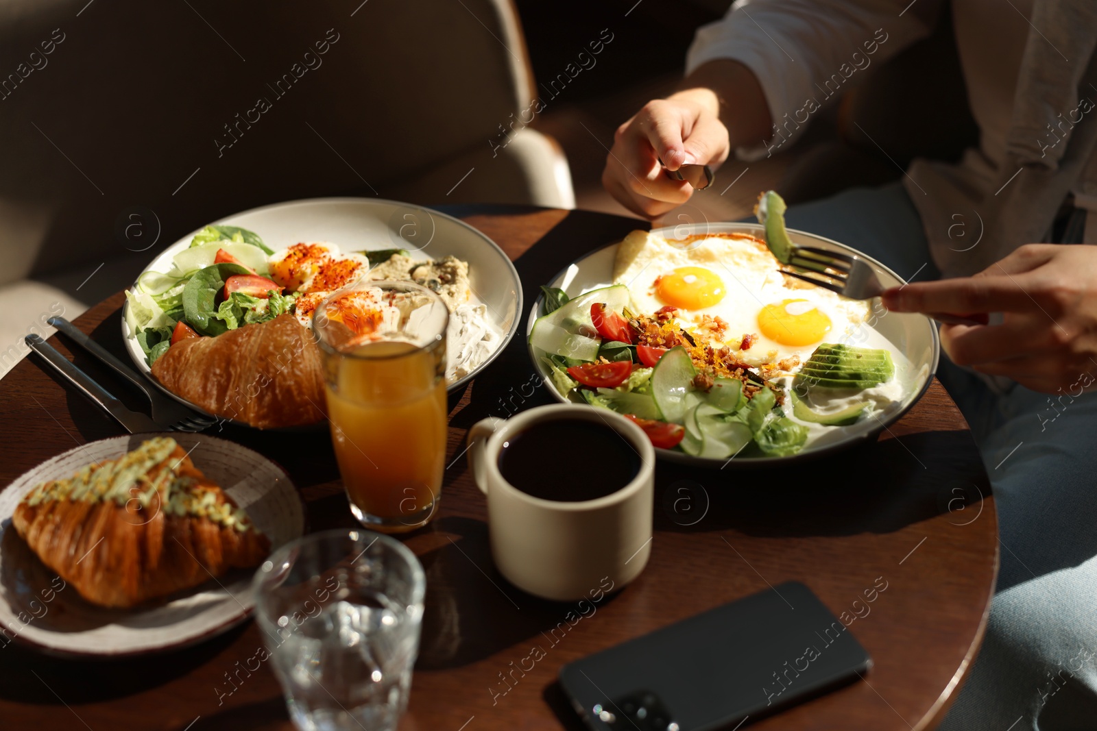 Photo of Man having tasty breakfast at wooden table in cafe, closeup