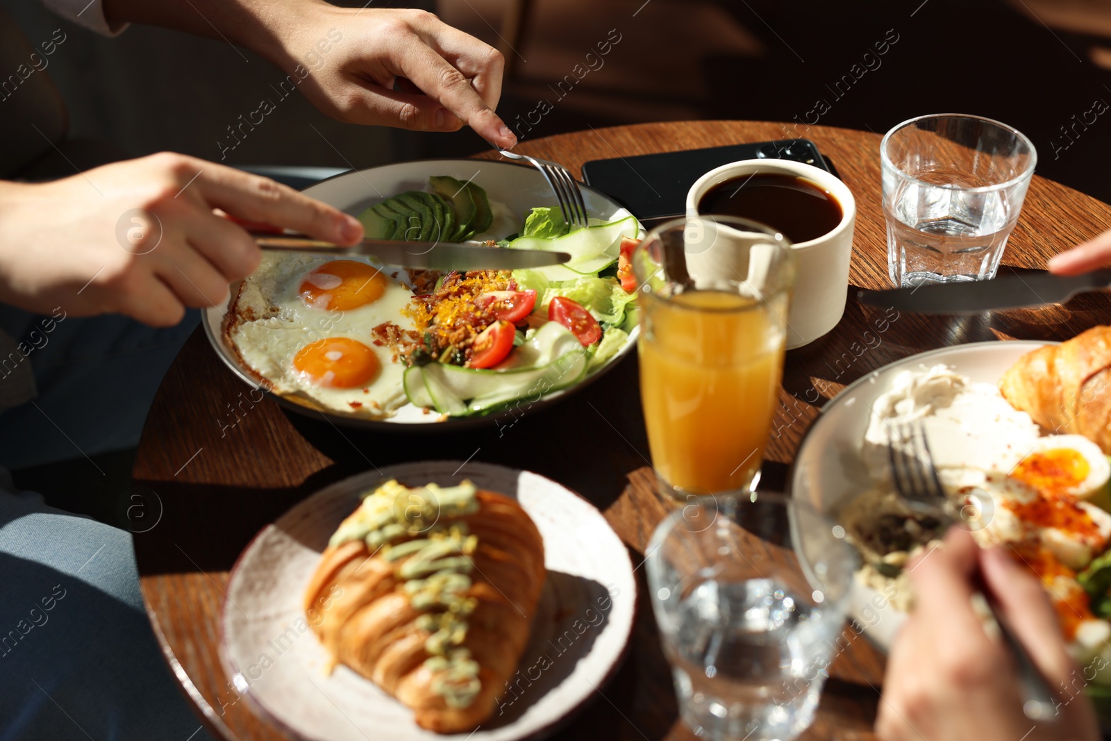 Photo of Couple having tasty breakfast at wooden table in cafe, closeup