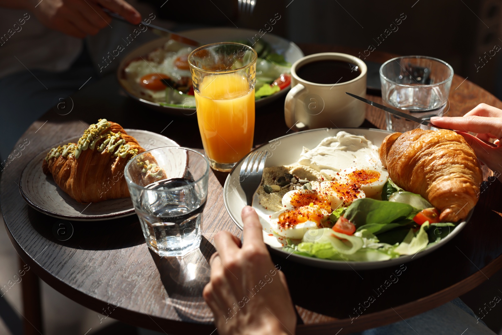 Photo of Couple having tasty breakfast at wooden table in cafe, closeup