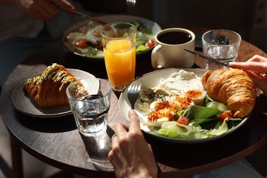 Photo of Couple having tasty breakfast at wooden table in cafe, closeup