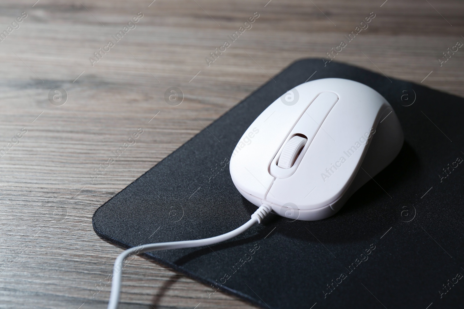 Photo of Computer mouse with mousepad on wooden table, closeup. Space for text