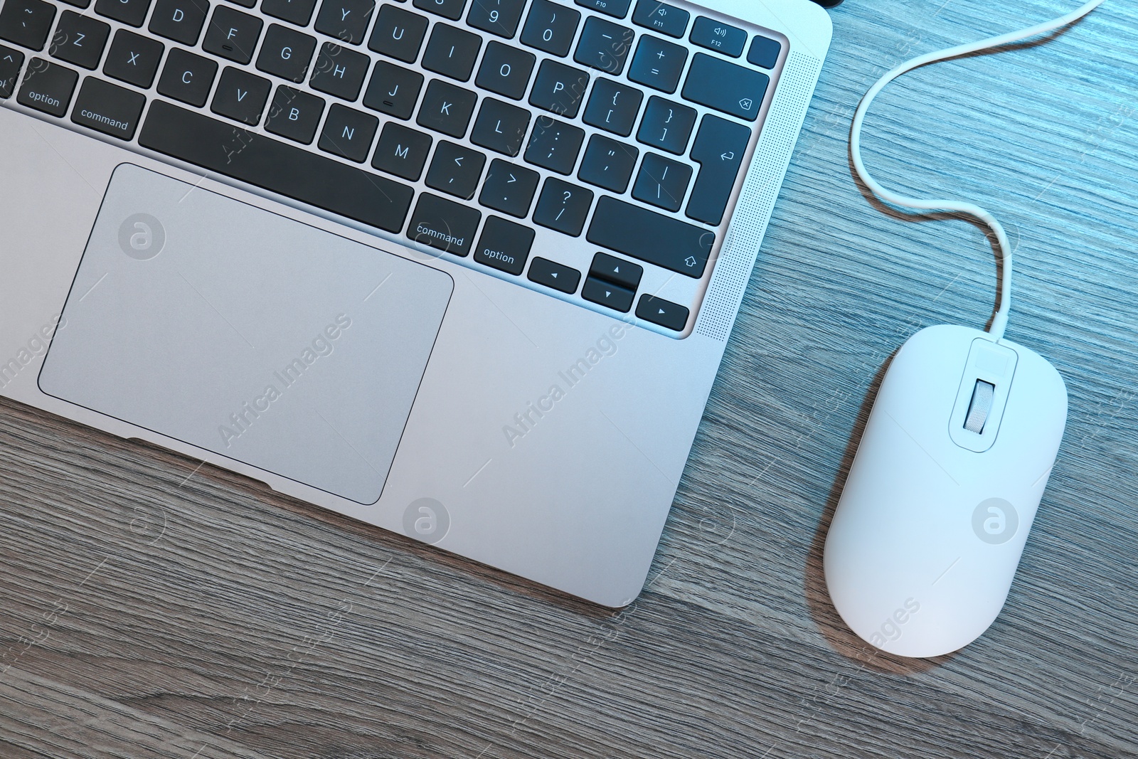 Photo of Computer mouse and laptop on wooden table, flat lay