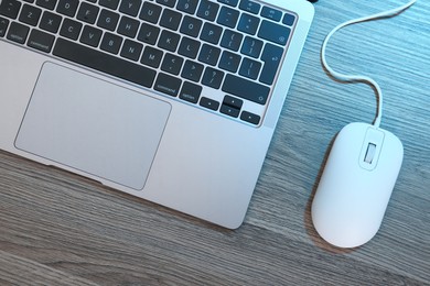 Photo of Computer mouse and laptop on wooden table, flat lay