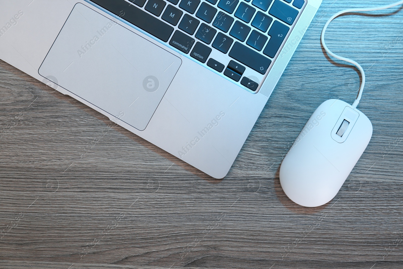 Photo of Computer mouse and laptop on wooden table, flat lay