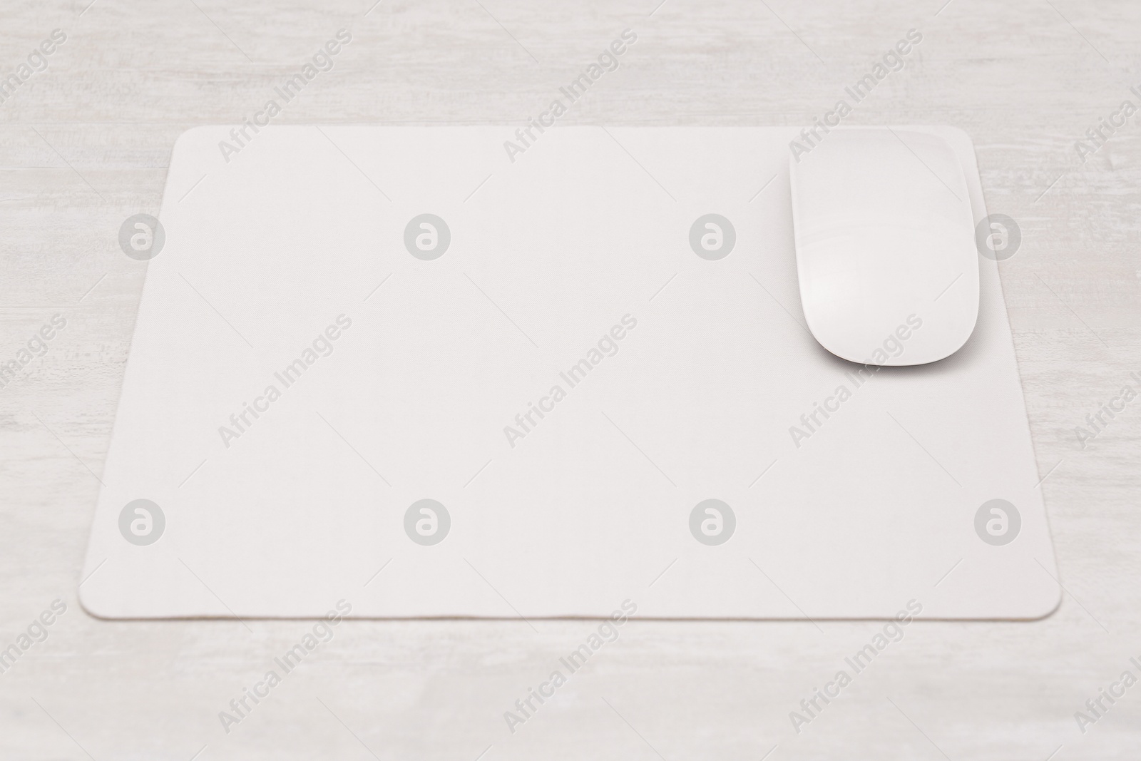 Photo of Computer mouse with mousepad on light wooden table