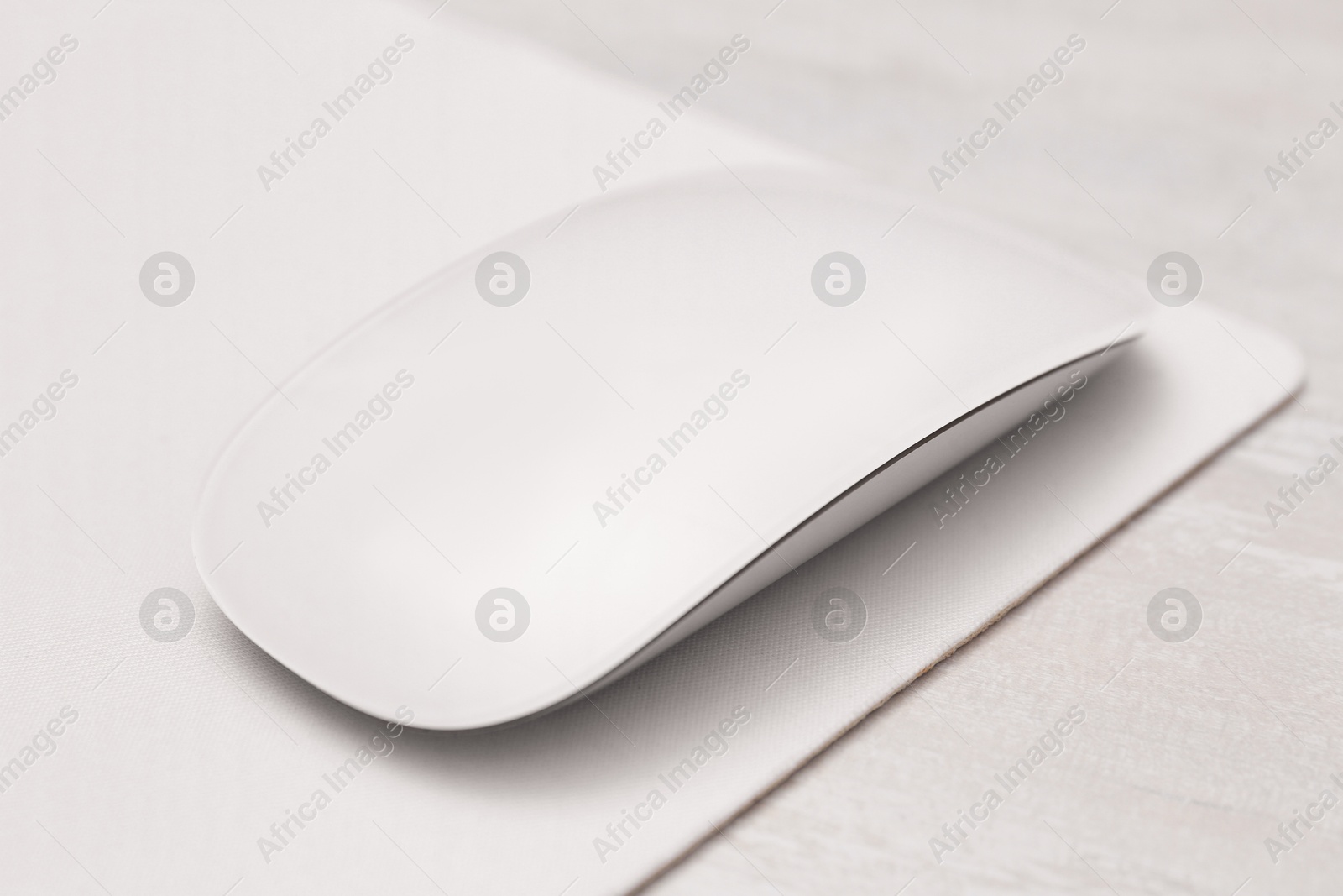 Photo of Computer mouse with mousepad on light wooden table, closeup