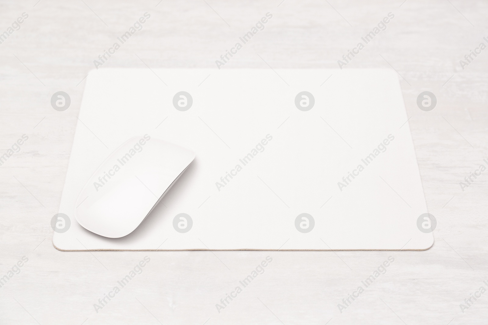 Photo of Computer mouse with mousepad on light wooden table