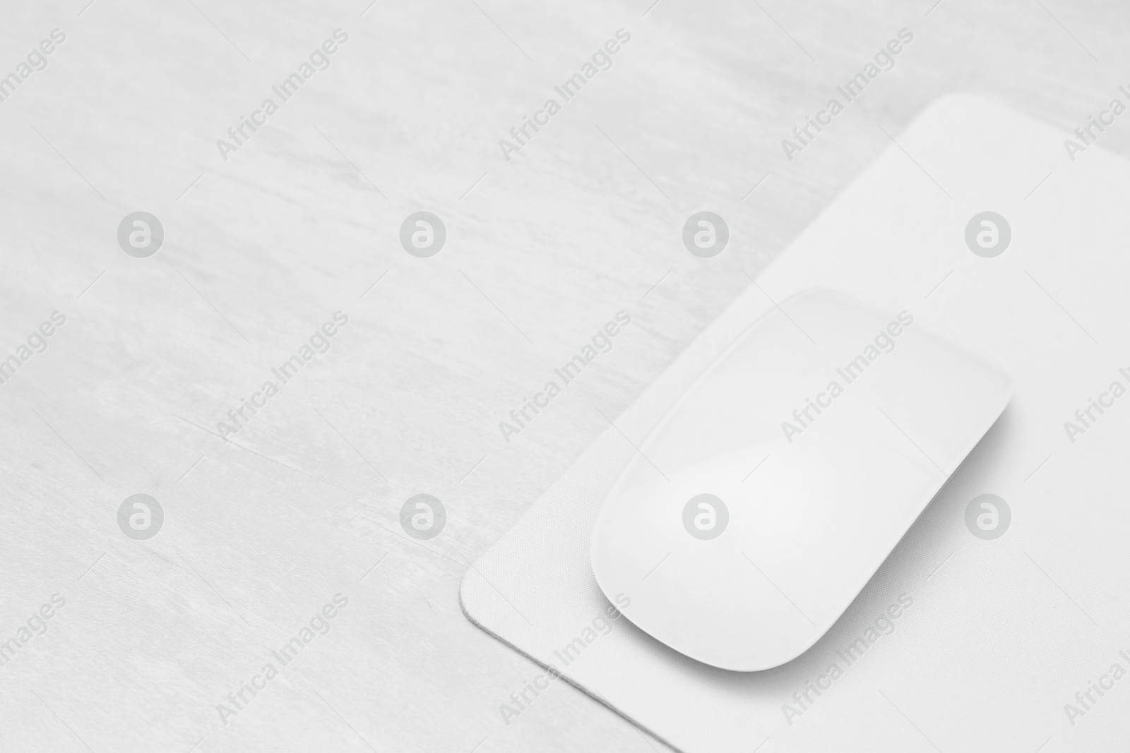 Photo of Computer mouse with mousepad on light wooden table, closeup. Space for text