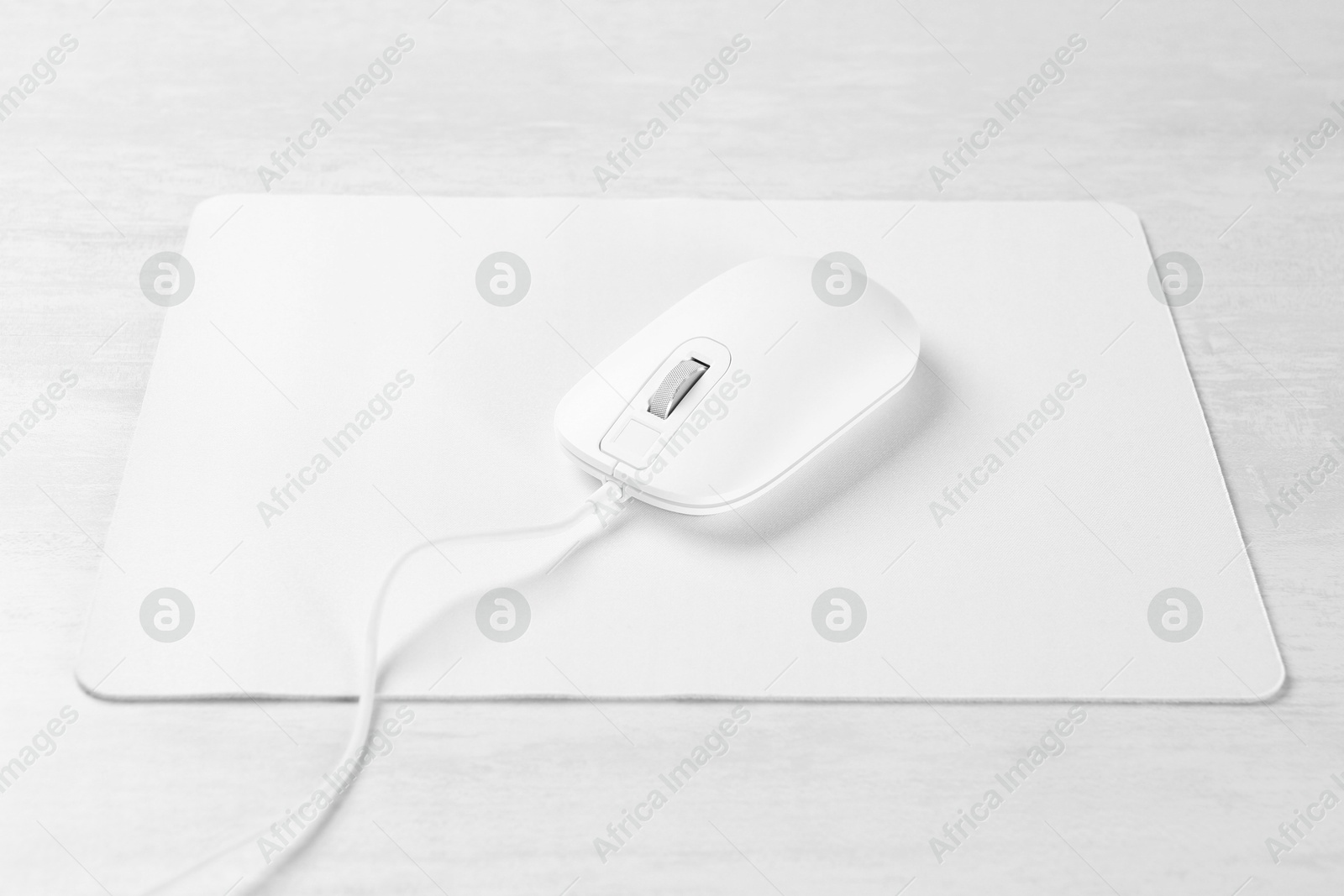 Photo of Computer mouse with mousepad on light wooden table