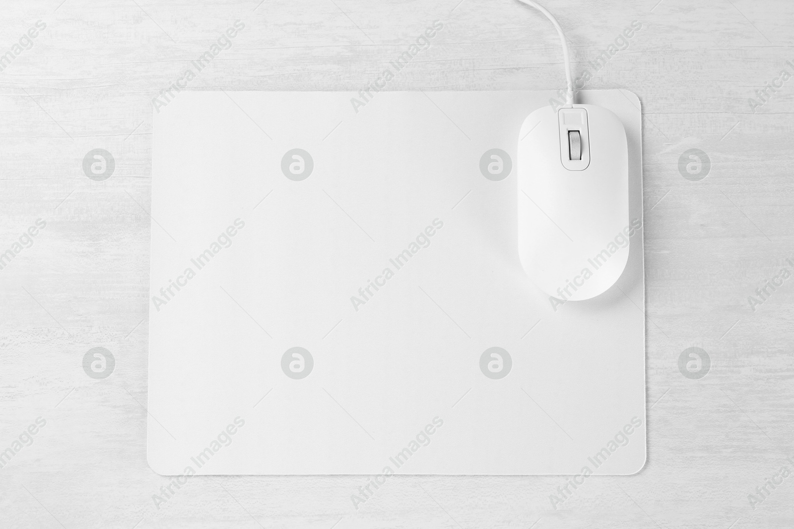 Photo of Computer mouse with mousepad on light wooden table, top view