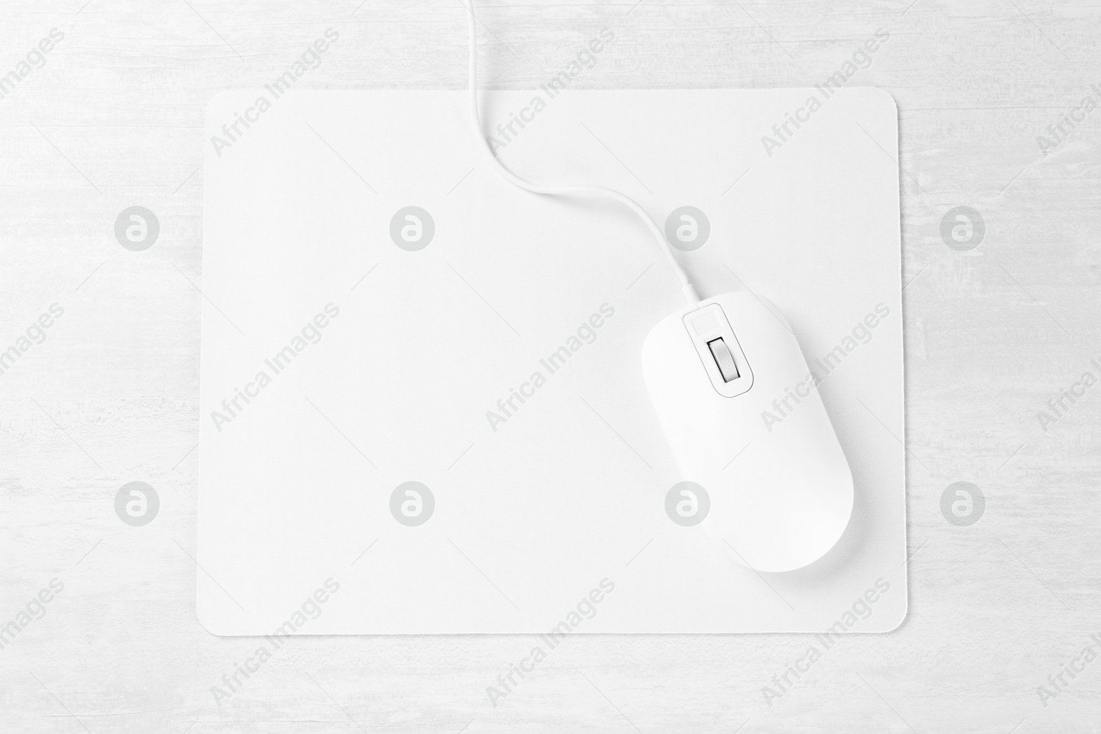 Photo of Computer mouse with mousepad on light wooden table, top view