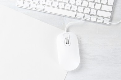 Photo of Computer mouse with mousepad and keyboard on light wooden table, flat lay