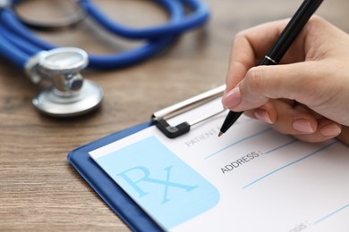 Photo of Doctor writing prescription at wooden table in clinic, closeup