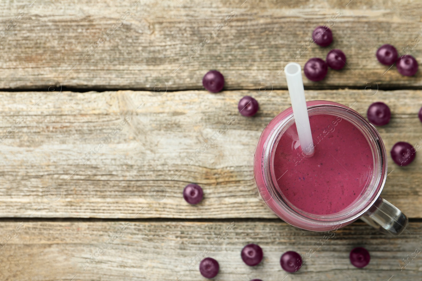 Photo of Tasty fresh acai juice in mason jar on wooden table, top view. Space for text