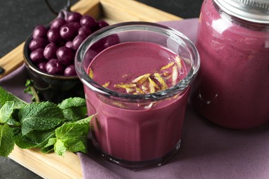 Photo of Tasty fresh acai juice with lemon zest, mint and berries on grey table, closeup