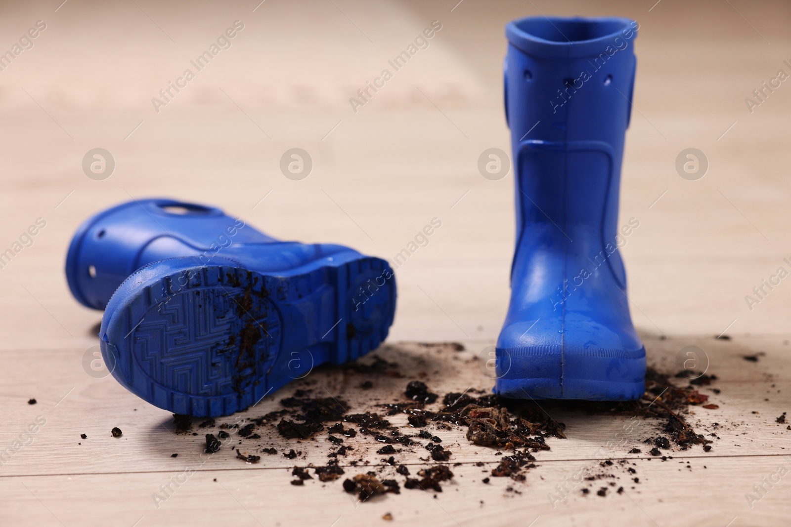 Photo of Rubber boots with mud on wooden floor