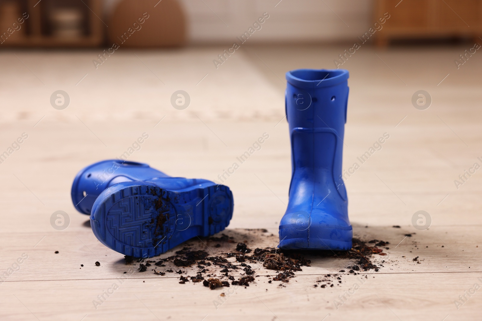 Photo of Rubber boots with mud on wooden floor